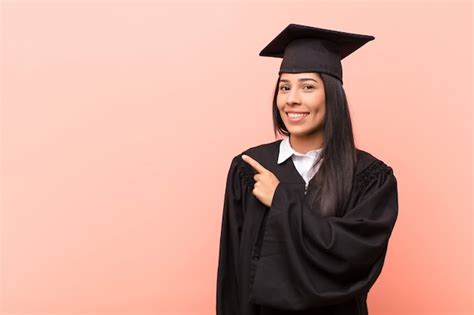 Joven estudiante latina sonriendo alegremente sintiéndose feliz y apuntando hacia un lado y
