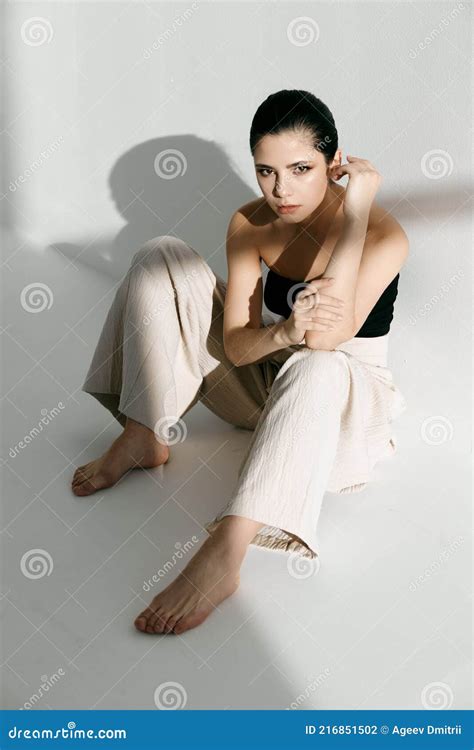 Barefoot Woman Sitting On The Floor Leaning Against The Wall Indoors