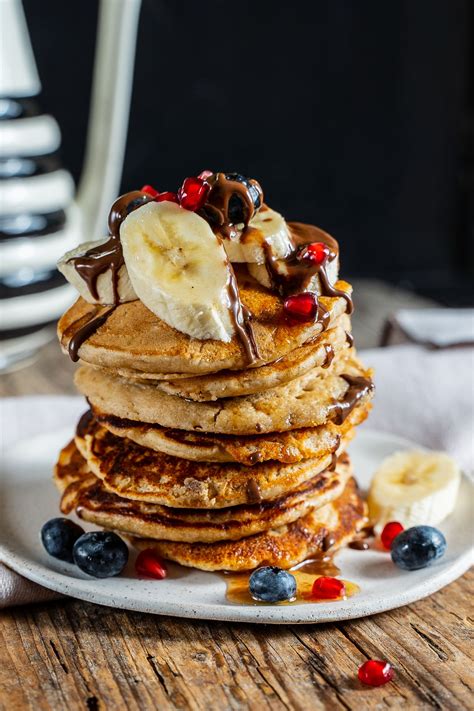 A Stack Of Pancakes Topped With Bananas And Blueberries