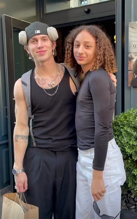 A Man And Woman Standing Next To Each Other In Front Of A Building With