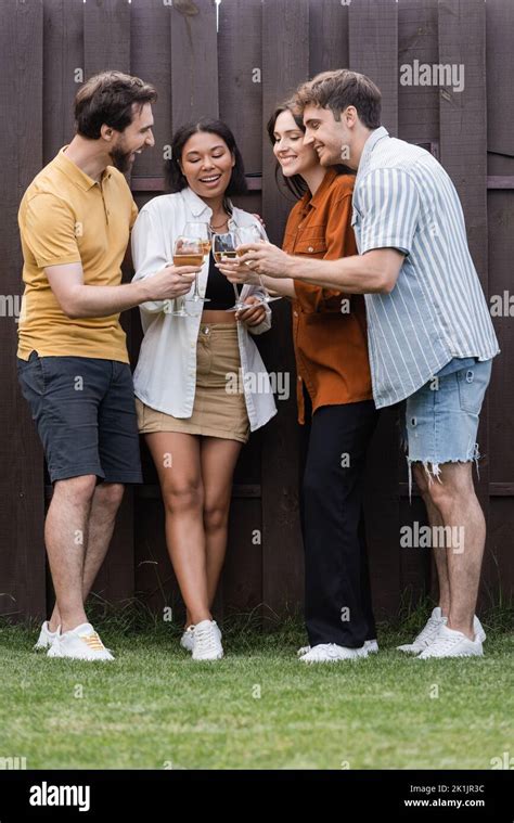 Full Length Of Happy Interracial Friends Clinking Glasses With Wine