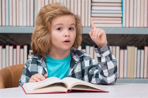 Criança Com Livro - Criança lendo um livro em uma biblioteca escolar conceito de educação ...