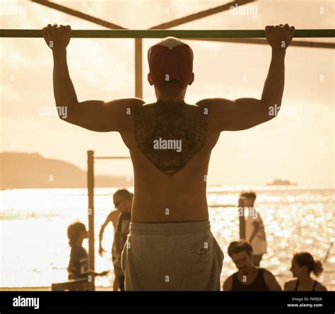 Rear View Of Muscular Man With Back Tattoo Doing Pull Upschin Ups On