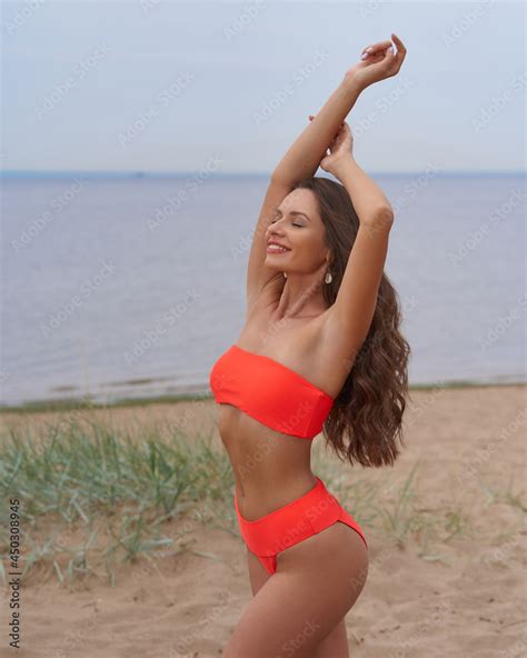 Foto De Sexy Tanned Caucasian Woman With Long Wavy Brunette Woman In Orange Bikini Swimsuit