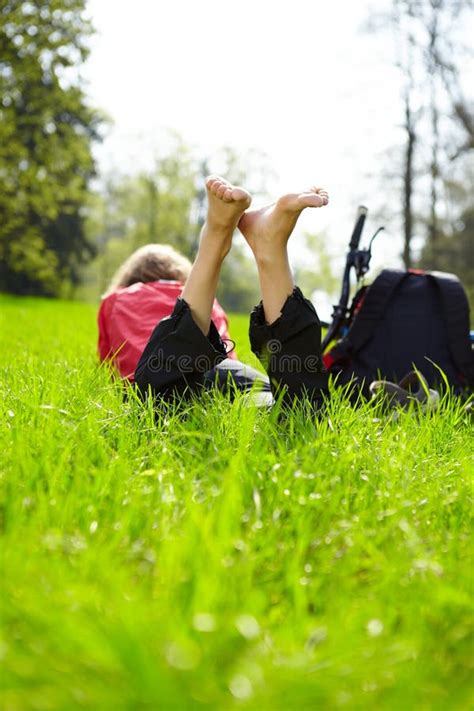 Joyful Tourist Enjoying Relaxation Lying Barefoot In Green Grass Stock