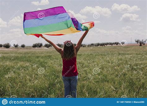 Mulher Que Guarda A Bandeira Alegre Do Arco Ris Em Um Prado Verde Fora