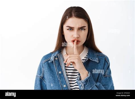 Angry young woman shushing, frowning and make shhh hush gesture with ...