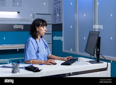 Healthcare Nurse Working With Monitor And Keyboard In Doctors Office