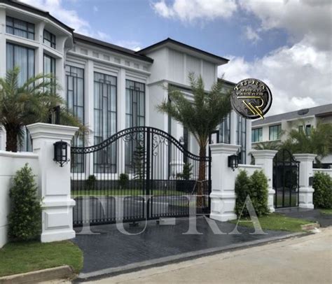 A Large White Building With Black Gate And Palm Trees