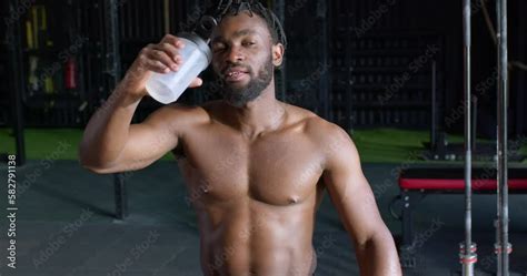Muscular African American Male Bodybuilder With Naked Torso Drinking Water Has Rest After