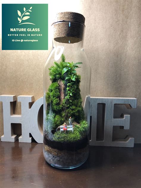 A Glass Jar Filled With Moss Sitting On Top Of A Wooden Table Next To A