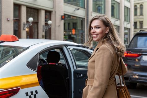 Une Belle Jeune Femme Monte Dans Un Taxi Jaune En Ville Blonde Souriante Dans Un Manteau Beige