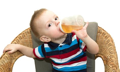 Der Kleine Blonde Junge Sitzt In Einem Geflochtenen Stuhl Und Trinkt Jui Stockfoto Bild Von