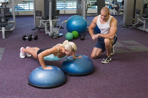 Premium Photo Male Trainer Assisting Woman With Push Ups At Gym