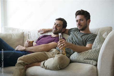 Gay Male Couple On Sofa At Home Watching TV Drinking Beer Stock Photo Adobe Stock
