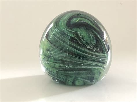 A Green Marble Sitting On Top Of A White Table Next To A Black And White Object