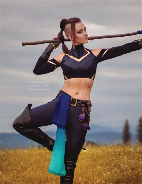 A Woman In Black And Blue Outfit Holding A Baseball Bat Over Her Head While Standing On Top Of A