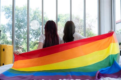 Premium Photo The Lgbt Couple Sat On The Bed Covered In Rainbow Flags Peering Out The Window