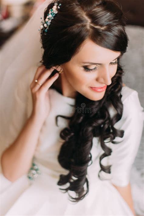 Closeup Of Elegant Sensual Brunette Bride In Beautiful White Dress Posing Indoor Sitting On Bed