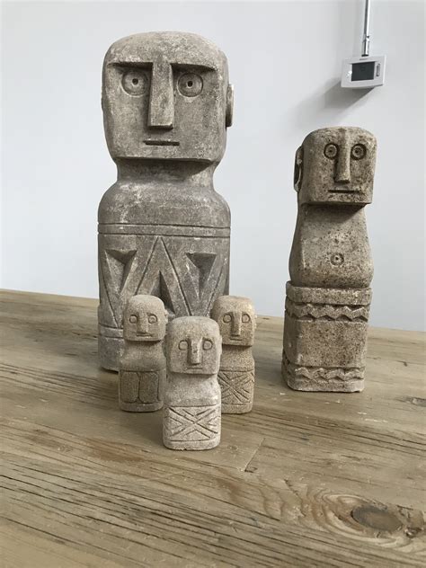 Three Stone Statues Sitting On Top Of A Wooden Table