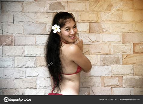 Portrait Of Pretty Asian Woman In Sexy Red Bikini Posing And Standing Front On The Wall Stock
