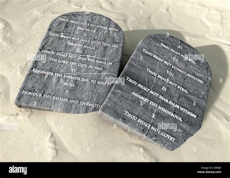 Two stone tablets with the ten commandments inscribed on them lying on brown desert sand Stock ...