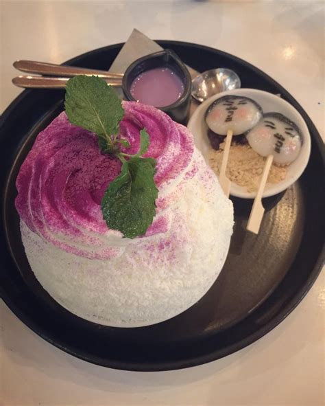 A Black Plate Topped With A Cake Covered In Pink And White Frosting