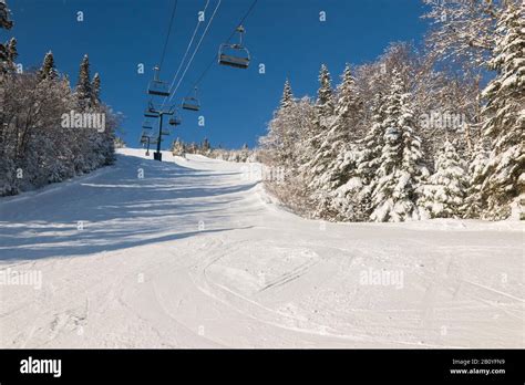 View Of Skiers On Ski Lift With Snow Covered Mountains Chairlift Above