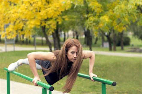 Beautiful Female Athlete Exercising On Parallel Bars Doing Push Ups