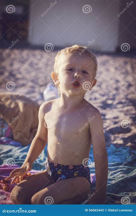 Pojke I Kortslutningar Som Sitter På Stranden Fotografering för