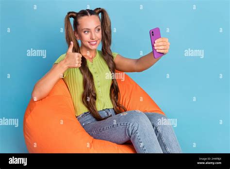 Photo Of Cool Millennial Brunette Lady Sit On Chair Do Selfie Show Thumb Up Wear Jeans T Shirt