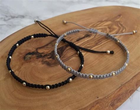 Two Bracelets Sitting On Top Of A Wooden Board