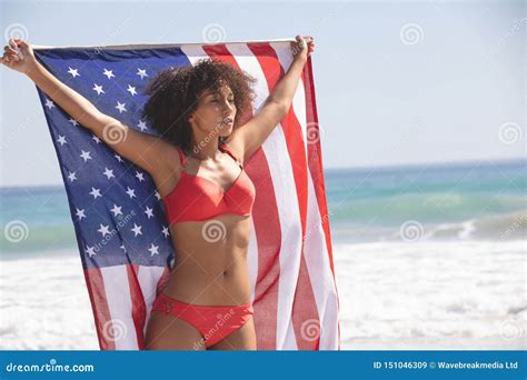 Mujer En El Bikini Que Sostiene La Bandera Americana En La Playa Imagen De Archivo Imagen De