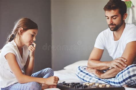 Thinking About Her Next Move A Young Father Playing A Board Game With