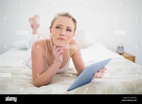 Natural Thoughtful Blonde Lying On Bed Holding Tablet Stock Photo Alamy