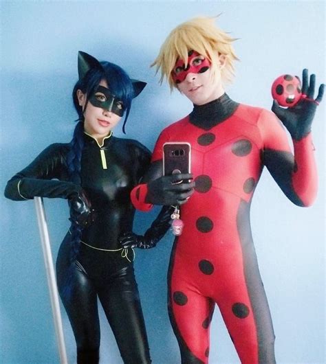 Two People Dressed Up As Ladybug And Catwoman With Cell Phones In Their