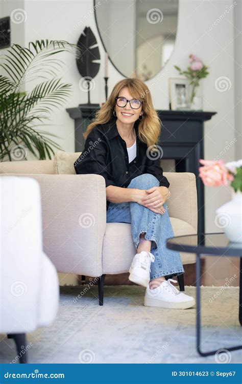 Pleine Longueur D Une Belle Femme Blonde Assise Dans Un Fauteuil Dans Sa Maison Moderne Image