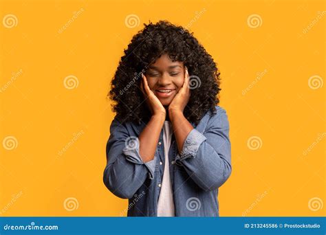 Smiling Young Black Woman With Closed Eyes Touching Her Face Stock