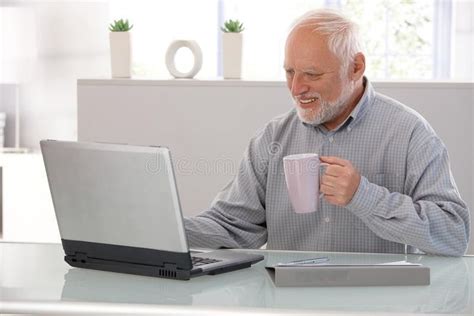 Elderly man working on laptop smiling. Elderly man working on laptop ...