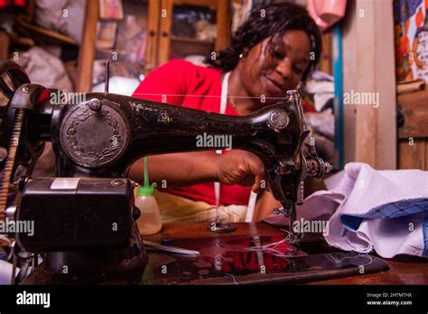 An African Seamstress Sews A Dress With Her Sewing Machine Working