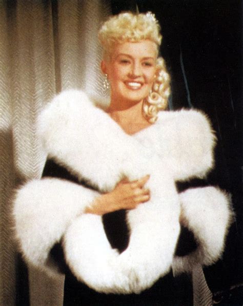 A Woman In A Black Dress And White Fur Stoler Posing For The Camera