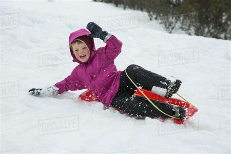 Cheerful Boy Tobogganing On Snow Covered Field Stock Photo Dissolve