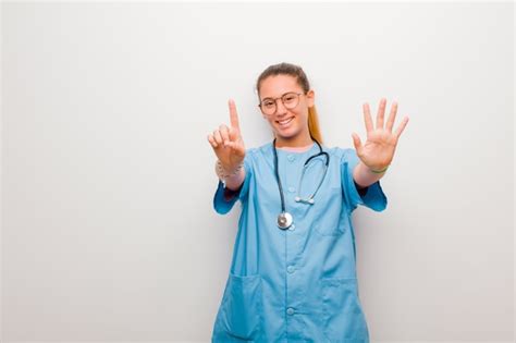 Jovem enfermeira latina sorrindo e olhando amigável mostrando o número seis ou sexto a mão