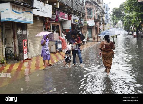 People Wade Through A Waterlogged Street During Heavy Rains In Kolkata