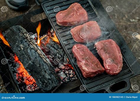 Beef Steaks Grilling On A Cast Iron Plate On A Camp Fire Campfire