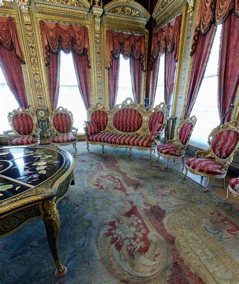 An Ornately Decorated Living Room With Red And Gold Chairs In Front Of