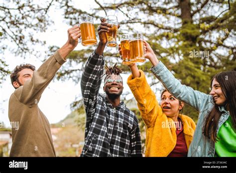 A Diverse Group Of Friends Raise Their Beer Glasses In A Toast Celebrating Together Amidst A