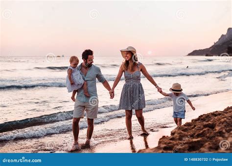 Familia Joven Con Dos Ni Os Del Ni O Que Caminan En La Playa El