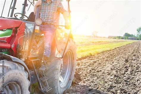 Mature Farmer Standing In Tractor With Yellow Lens Flare In Background Stock Photo Adobe Stock