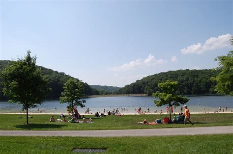 many people are sitting on the grass by the water and in the distance ...